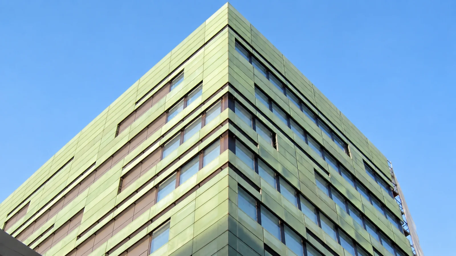 Gebäudeecke mit grün patinierter Kupferfassade vor blauem Himmel